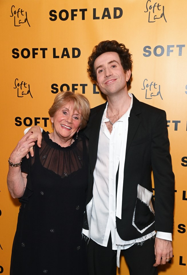 a man and woman are posing for a picture in front of a wall that says soft lad
