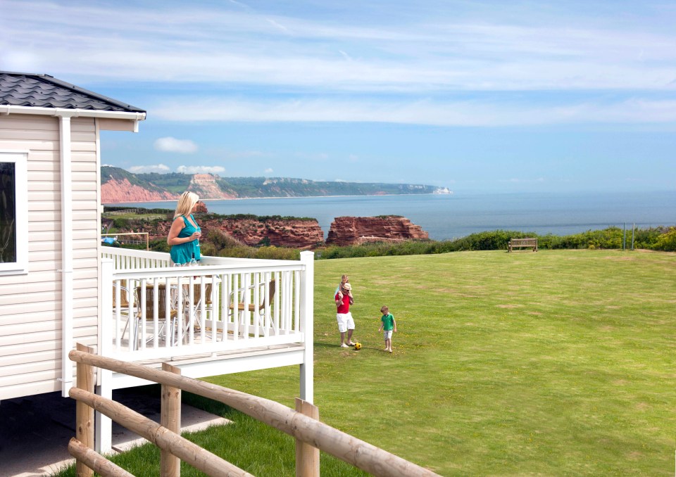 a woman stands on a balcony overlooking the ocean