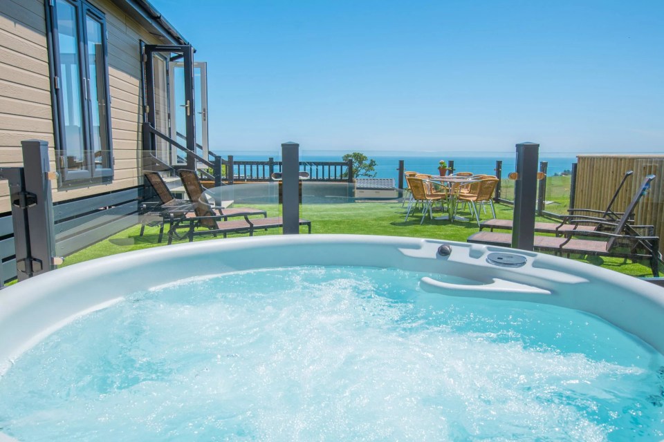 a hot tub in front of a house with a view of the ocean