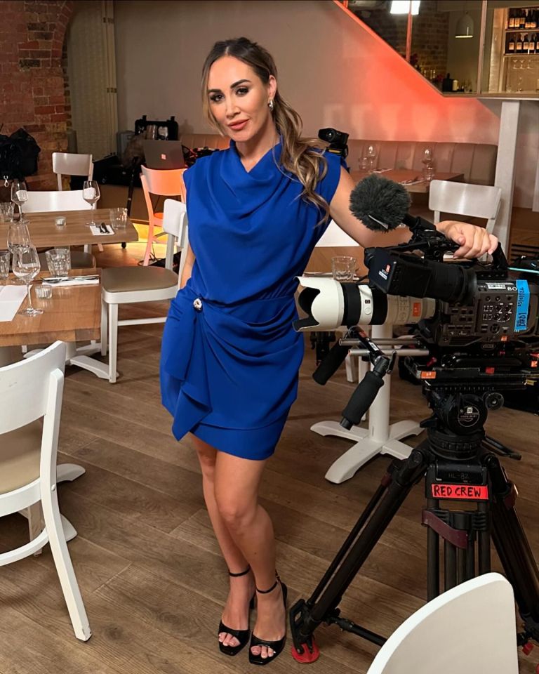 a woman in a blue dress stands in front of a red crew camera