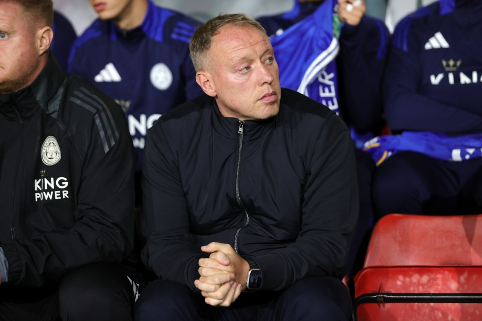 a man wearing a king power jacket sits in the stands