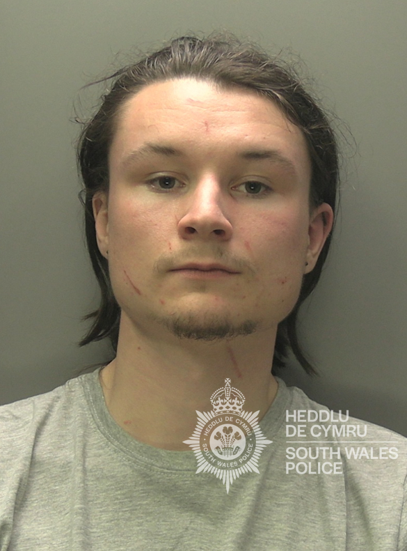 a man is wearing a grey shirt that says heddlu de cymru south wales police