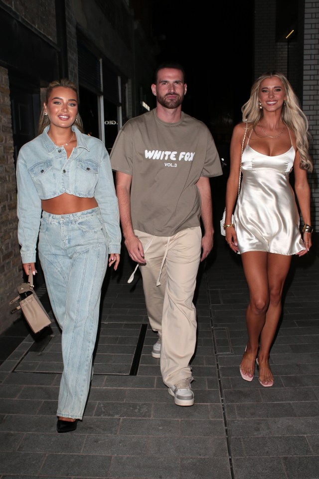 a man wearing a white fox t-shirt walks with two women