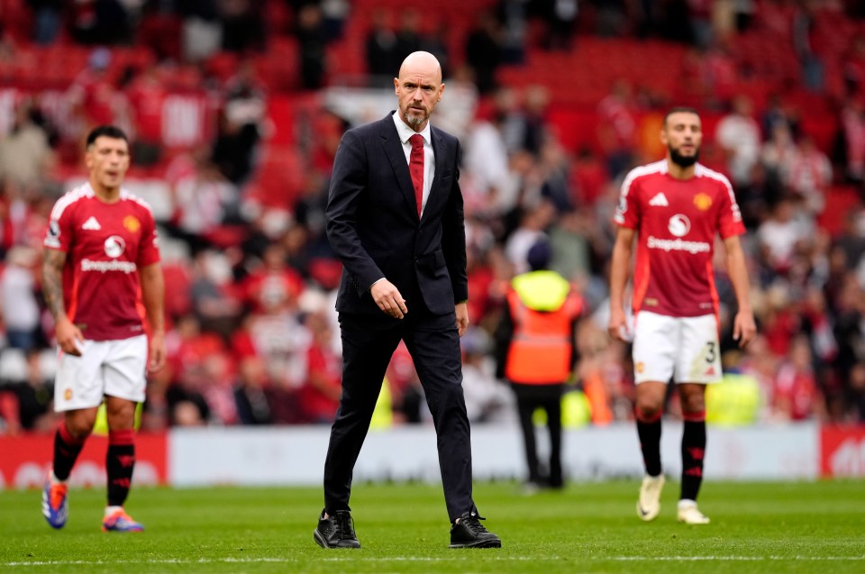 a man in a suit stands on a soccer field