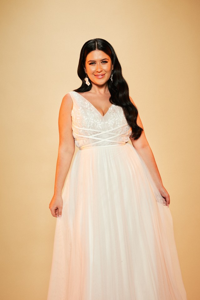 a woman in a white dress and earrings smiles for the camera
