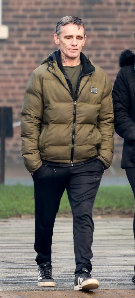 a man in a green jacket and black pants is walking