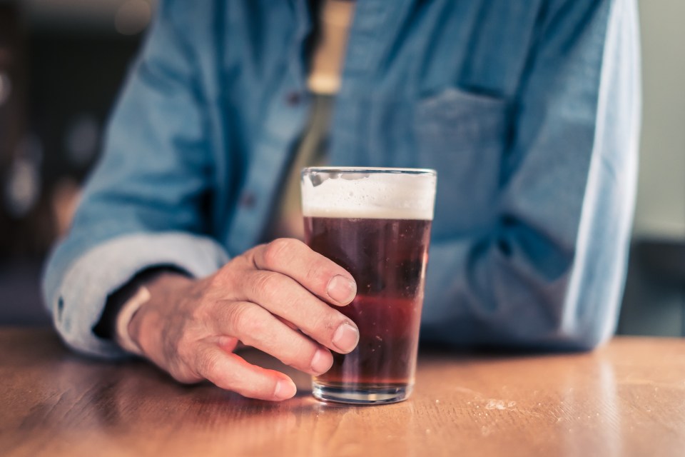 a man sitting at a table holding a glass of beer