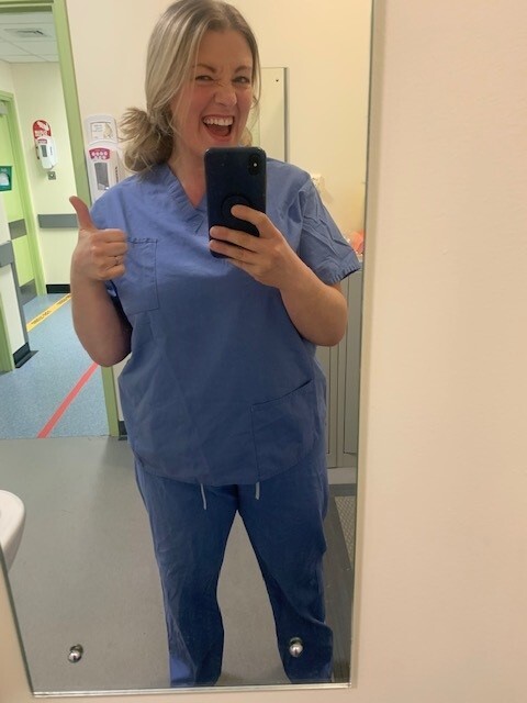 a woman in scrubs is taking a selfie in front of a mirror