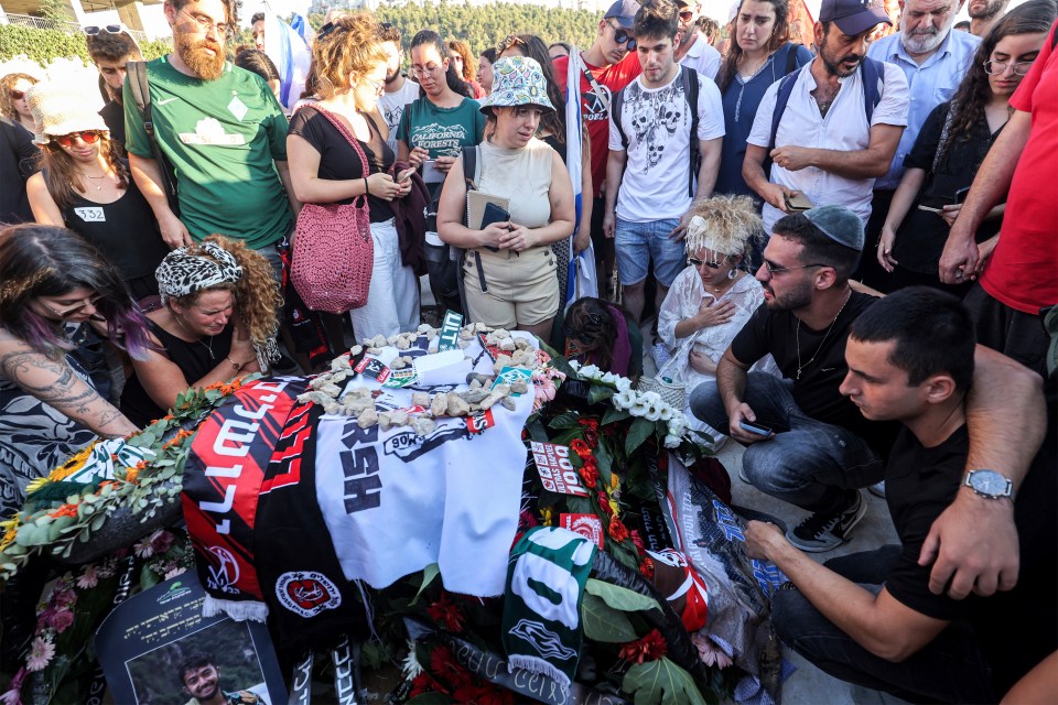 a group of people are gathered around a grave with a shirt that says hesh on it
