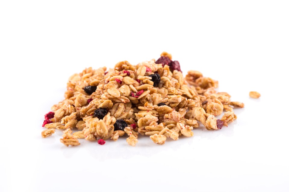 a pile of granola with blueberries and raspberries on a white background