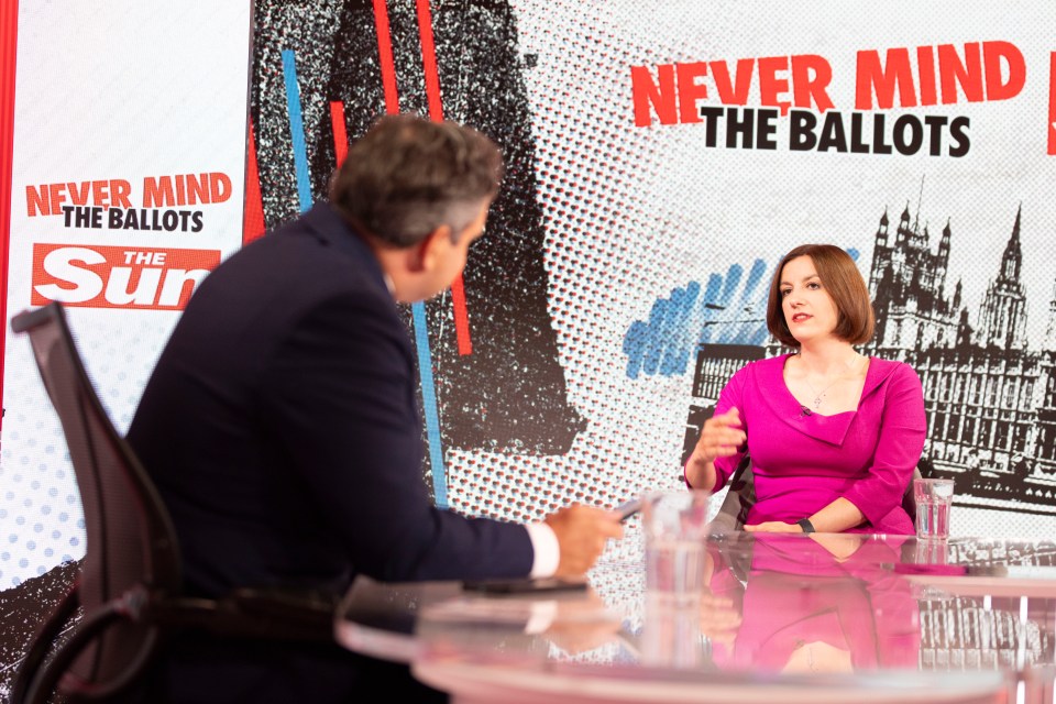 a man and woman sit at a table in front of a sign that says never mind the ballots
