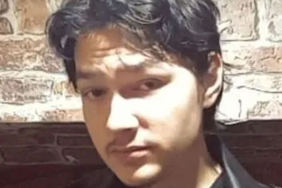 a young man is standing in front of a brick wall and looking at the camera .