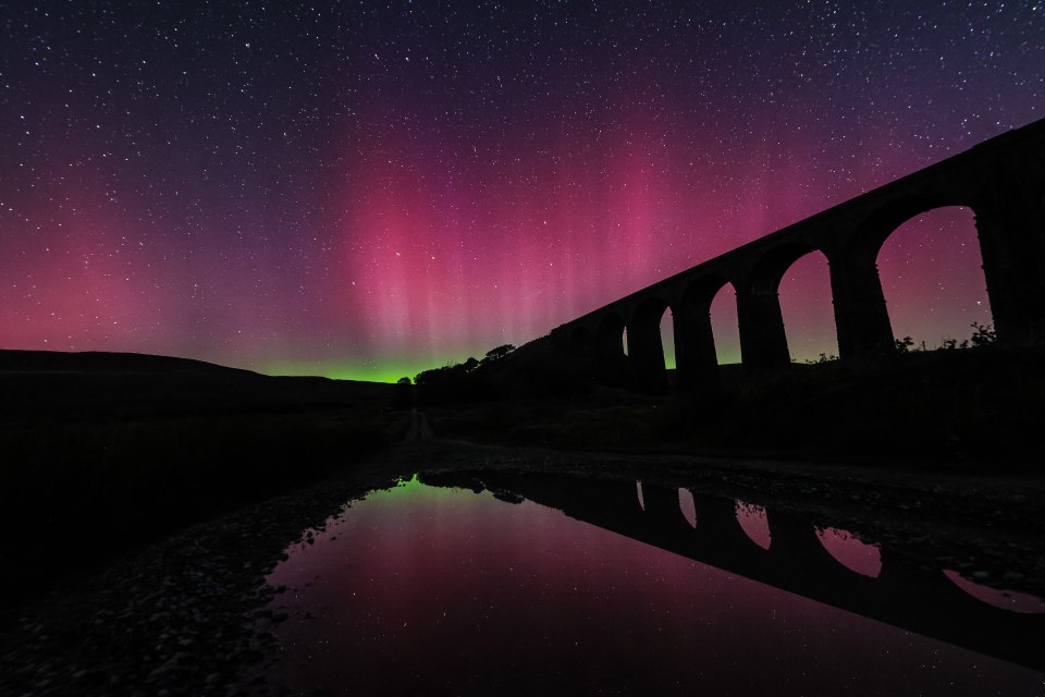 a bridge with the aurora borealis behind it