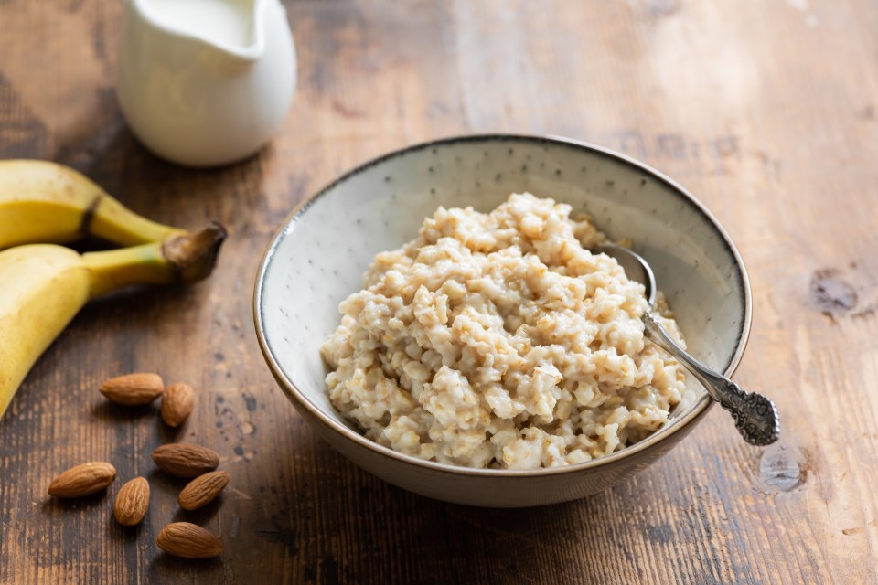 a bowl of oatmeal next to bananas and almonds