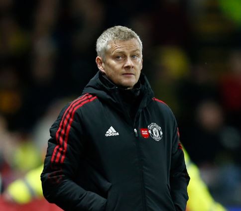 a man wearing a black jacket with red stripes is standing on a field .