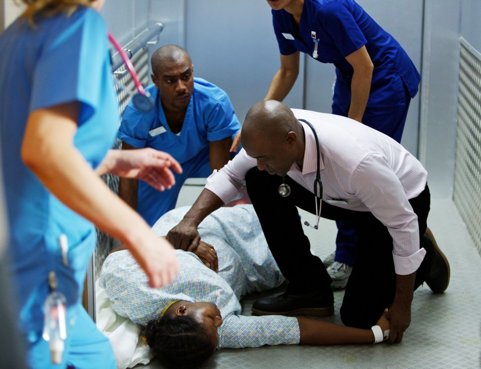 a man with a stethoscope is kneeling down next to a woman in a hospital bed