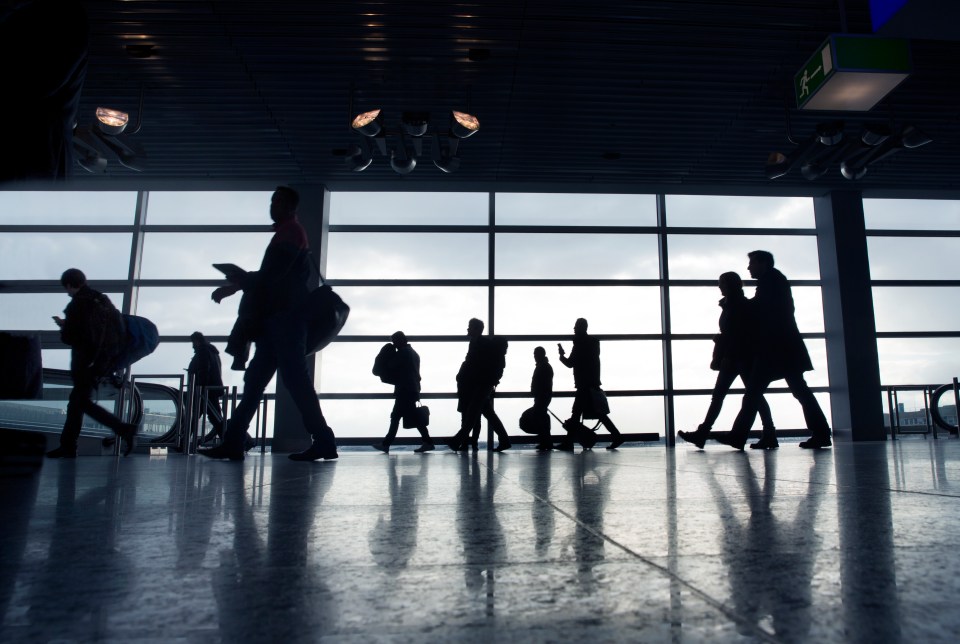 a group of people walking in front of a large window