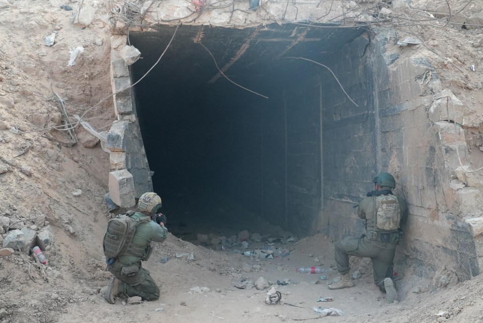 two soldiers are kneeling in front of a tunnel and one has a backpack that says ' tactical ' on it