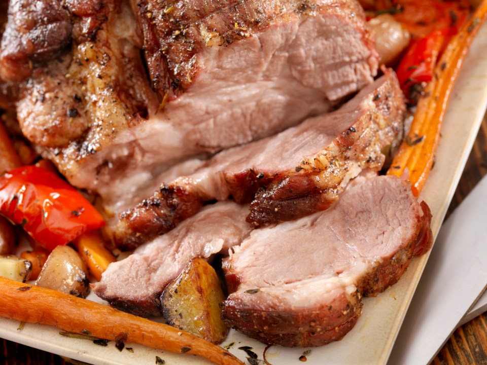 a piece of meat is on a plate with carrots and peppers