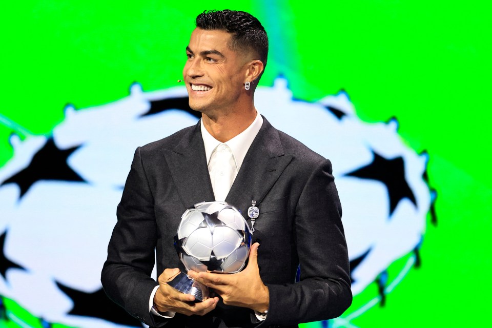 a man in a suit holds a soccer ball in front of a green background