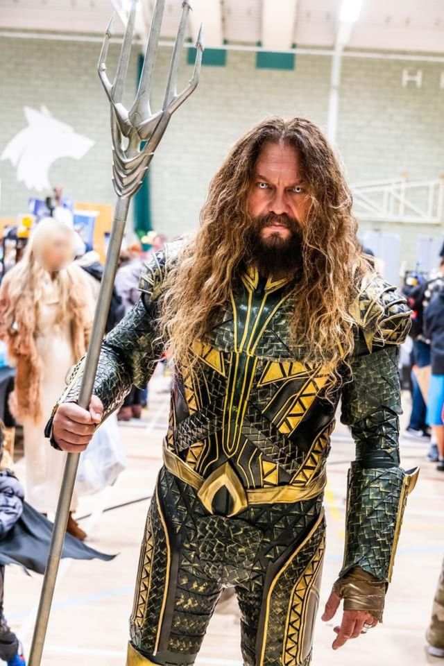 a man dressed as aquaman holds a trident
