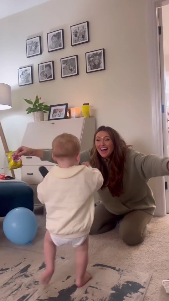 a woman is kneeling down next to a baby who is walking
