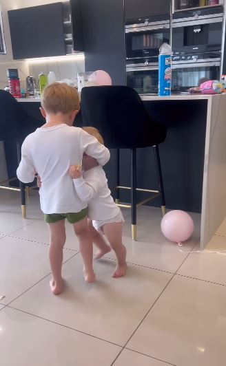 two young boys are standing next to each other in a kitchen .