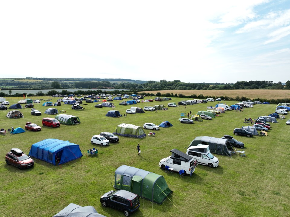 a large field filled with tents and cars on a sunny day