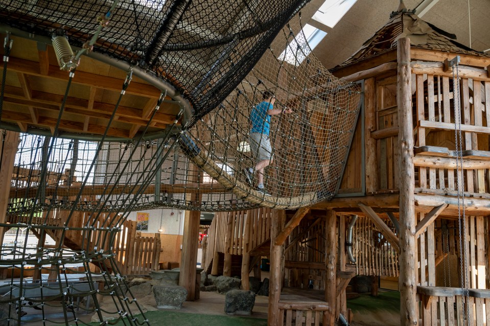 a boy stands on a rope bridge in a playground
