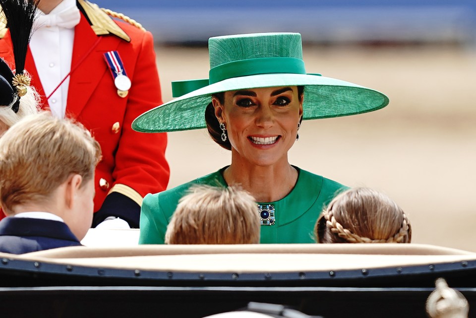 a woman wearing a green hat and earrings smiles for the camera