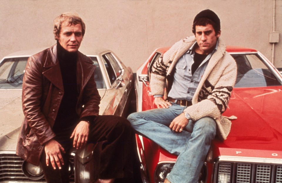two men sit on the hood of a red ford car