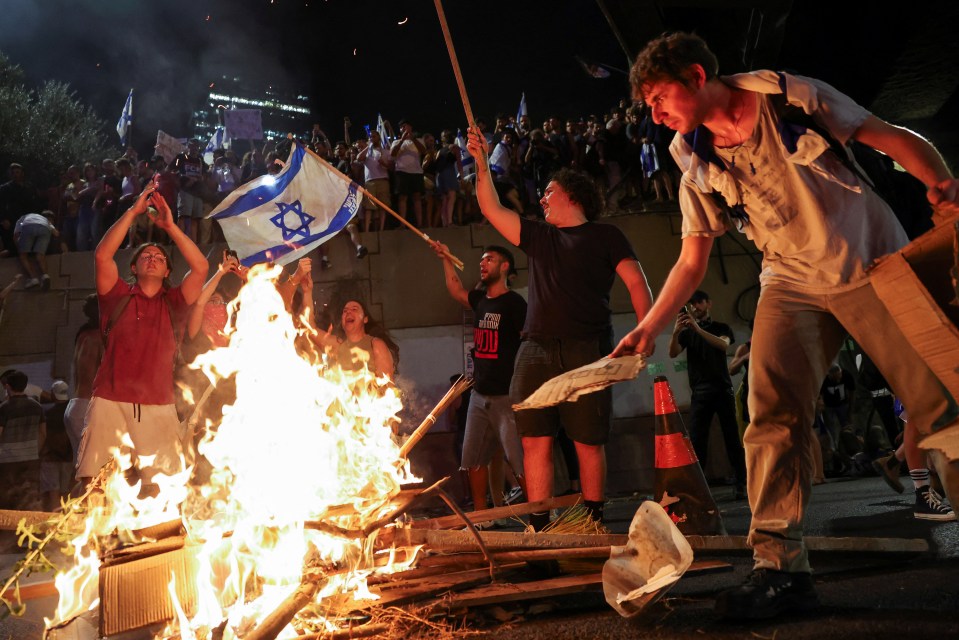 a group of people standing around a fire with one wearing a shirt that says ny