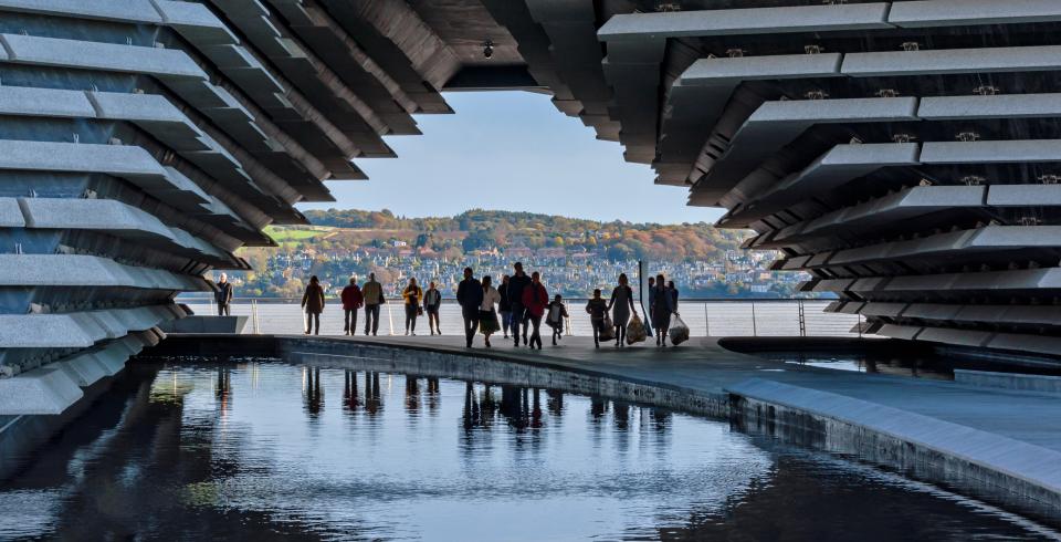 a group of people are walking across a bridge over a body of water