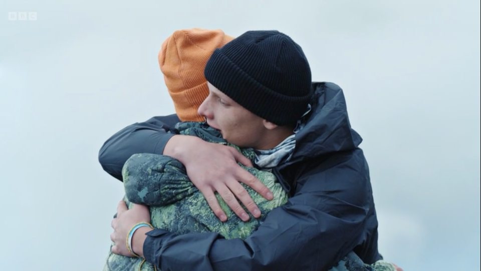 a man in a black hat is hugging another man in an orange hat
