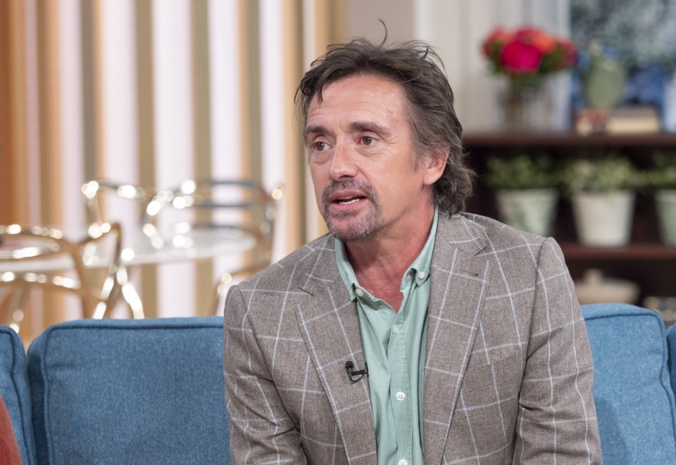 a man in a plaid suit sits on a blue couch