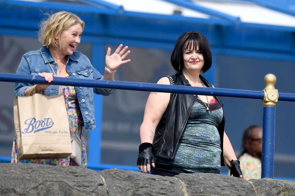 two women standing next to each other with a boots bag