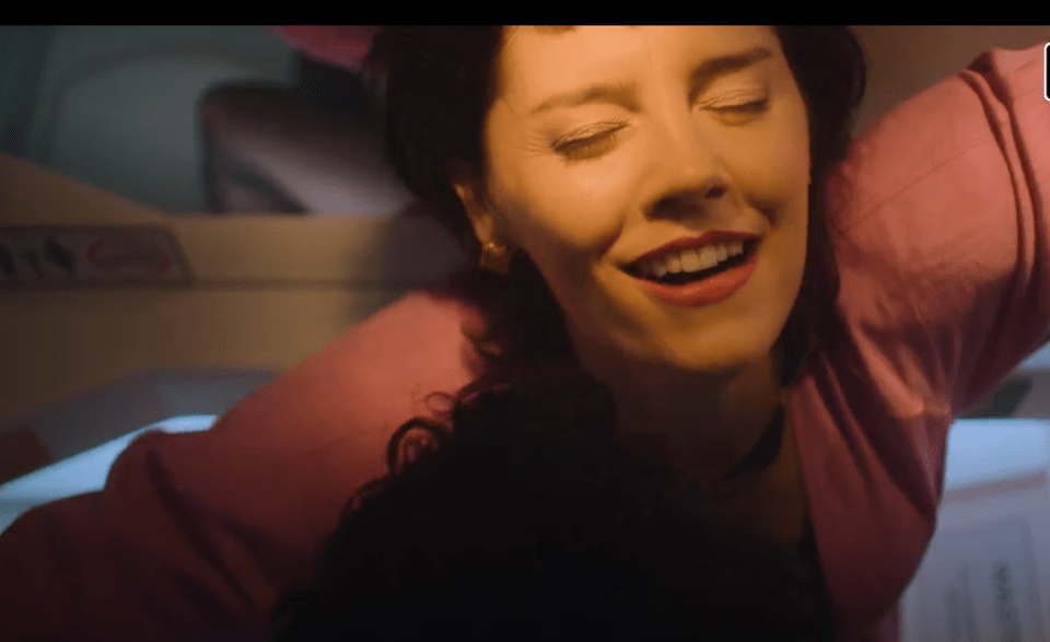 a woman in a pink shirt is smiling with her eyes closed