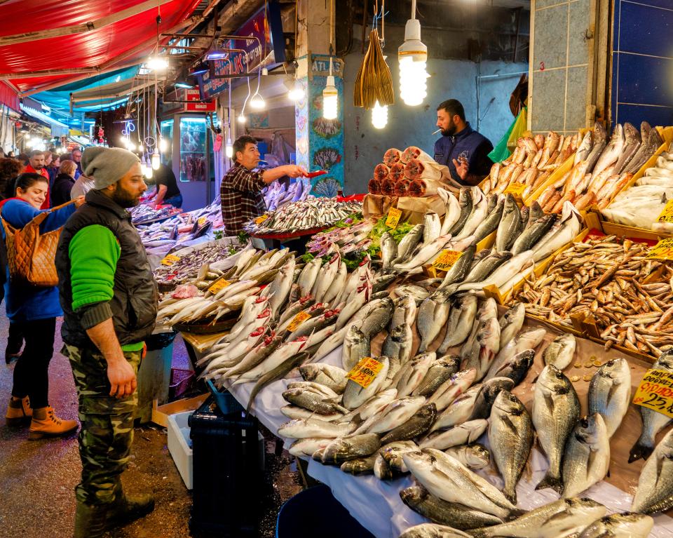 a man in a green vest stands in front of a display of fish