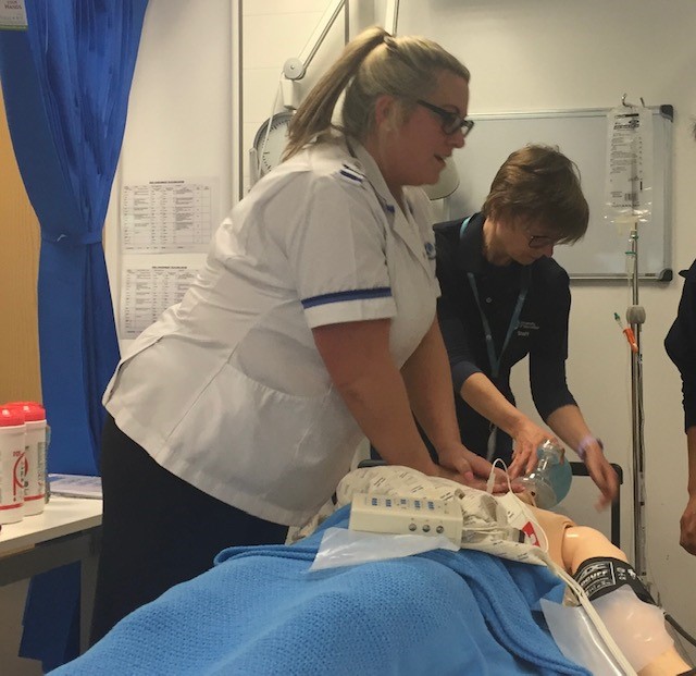 two nurses are working on a mannequin in a hospital room