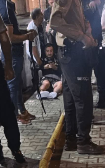 a group of people standing around a man who is laying on the ground