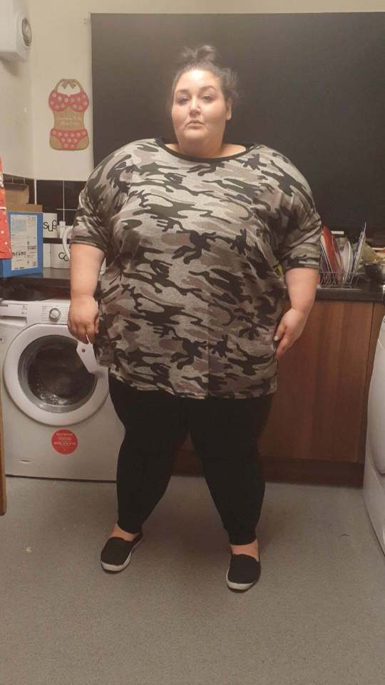 a woman in a camouflage shirt stands in front of a washing machine