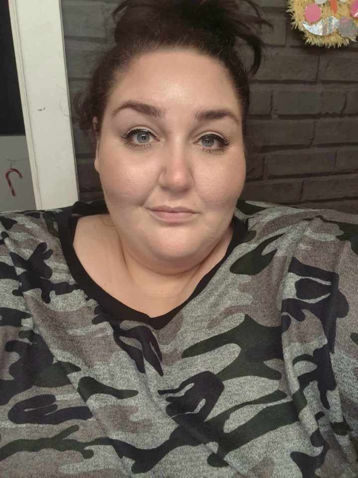 a woman wearing a camouflage shirt looks at the camera