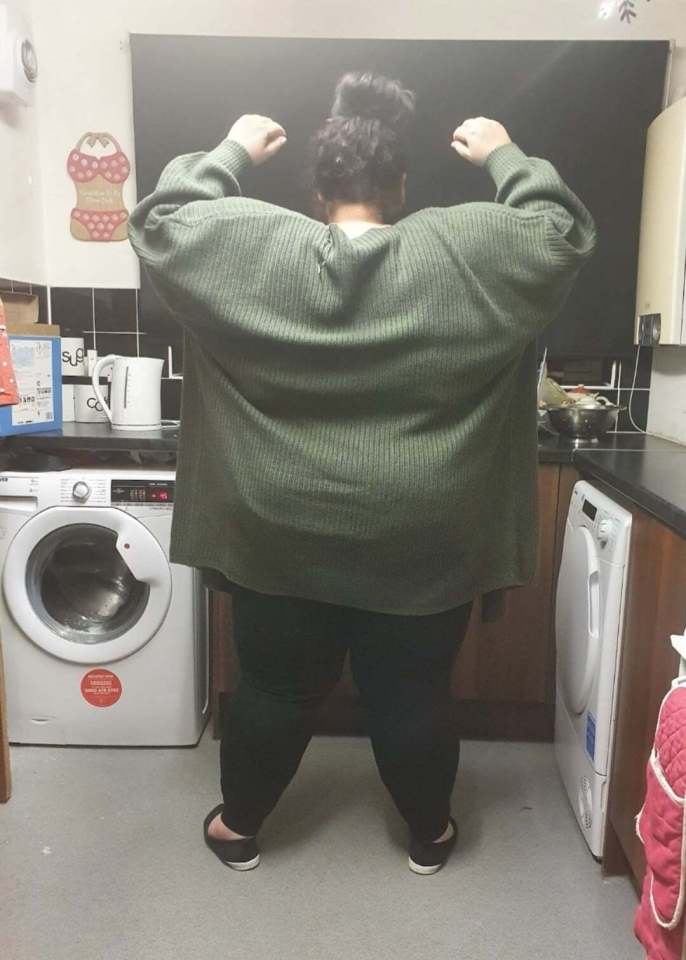 a woman in a green sweater stands in front of a samsung washing machine
