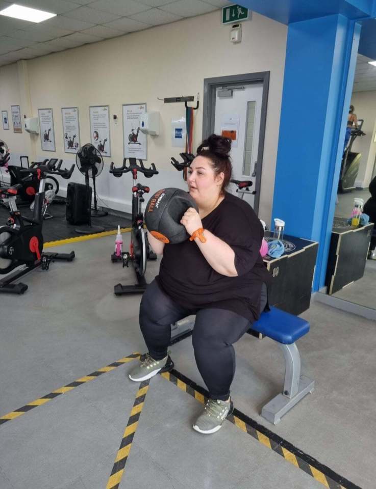 a woman is squatting on a bench in a gym