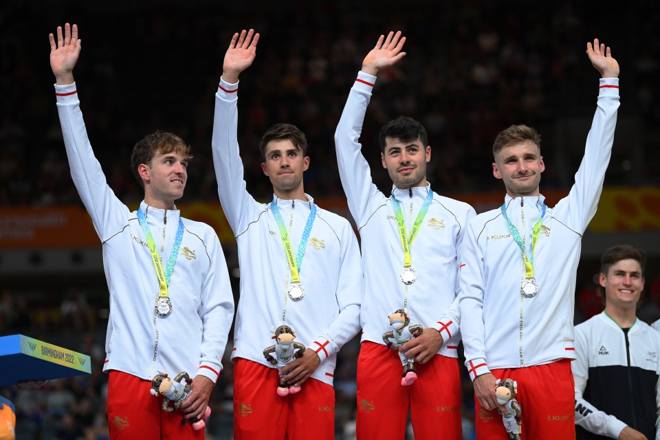 a group of athletes are standing on a podium with medals around their necks