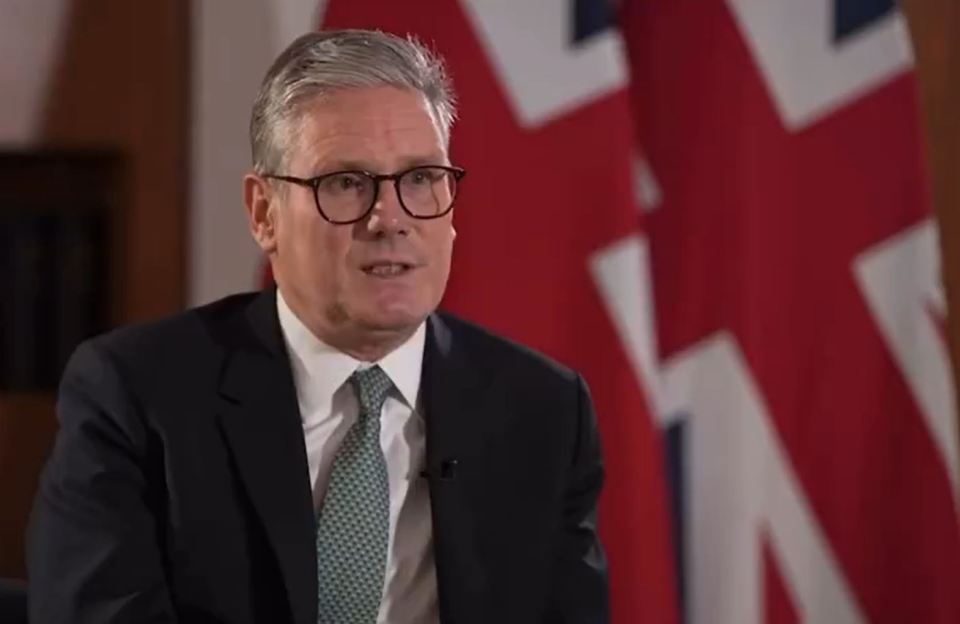 a man in a suit and tie is sitting in front of a flag