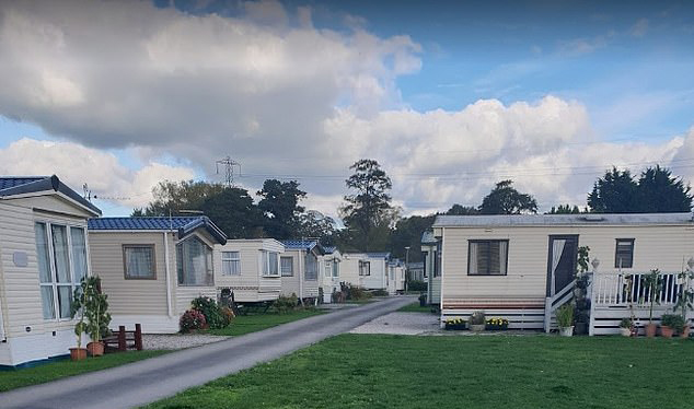 a row of mobile homes are parked on the side of a road in a residential area .