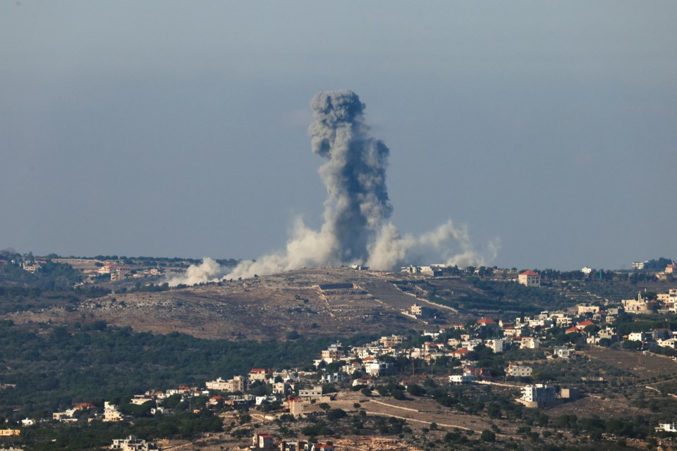a large cloud of smoke is coming out of a building on top of a hill