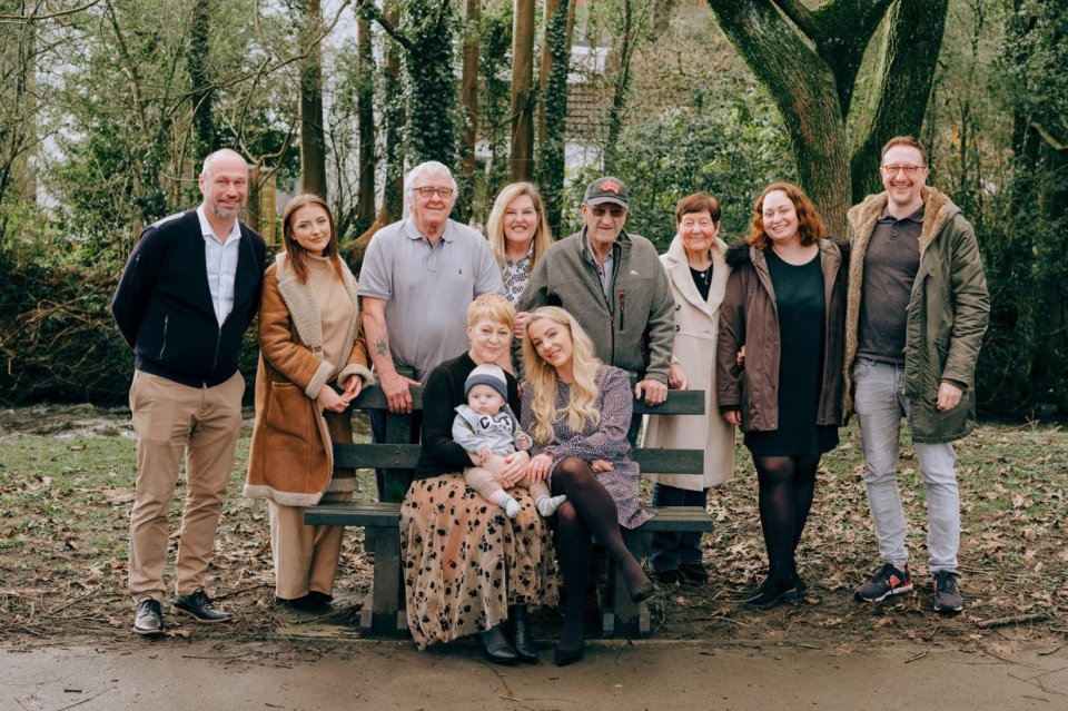 a group of people posing for a picture with a baby on a bench