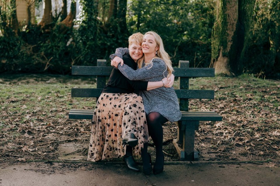 two women hugging each other while sitting on a park bench